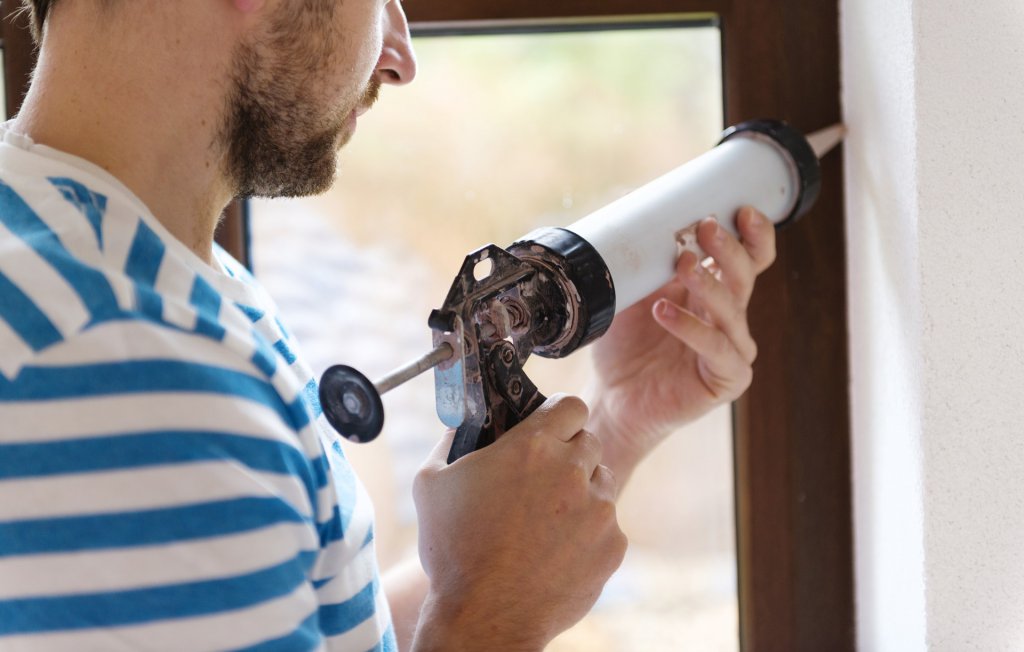 Man sealing cracks with a caulking gun